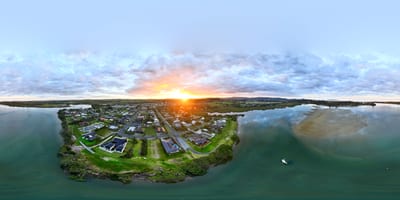 A panoramic view of a riverside town during sunset.